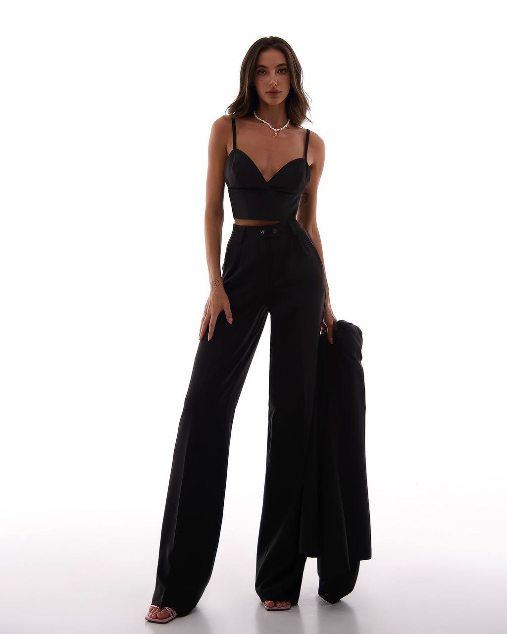 Woman wearing a black outfit with wide-leg pants on a white background