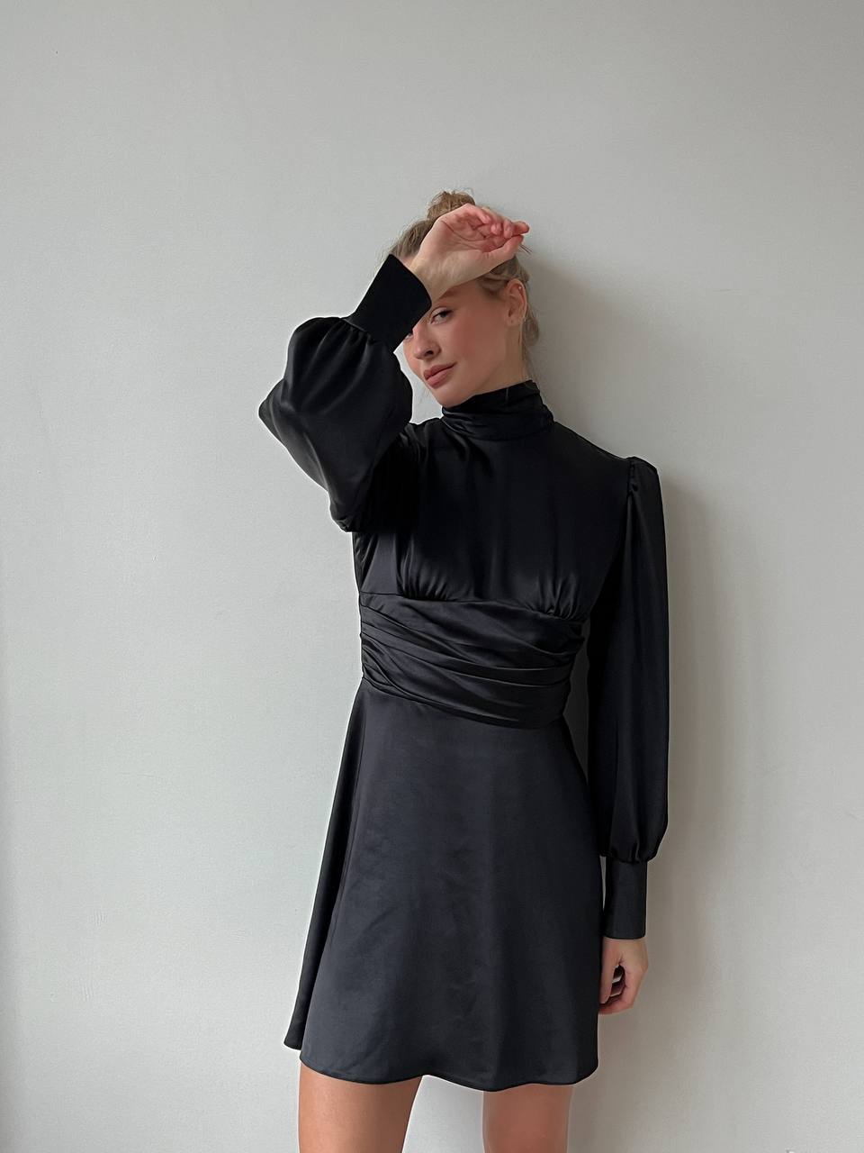 Person wearing a black dress against a plain background
