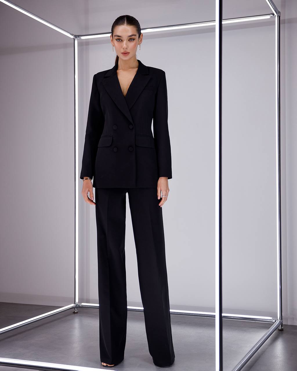 Person wearing a black suit standing inside a reflective box.