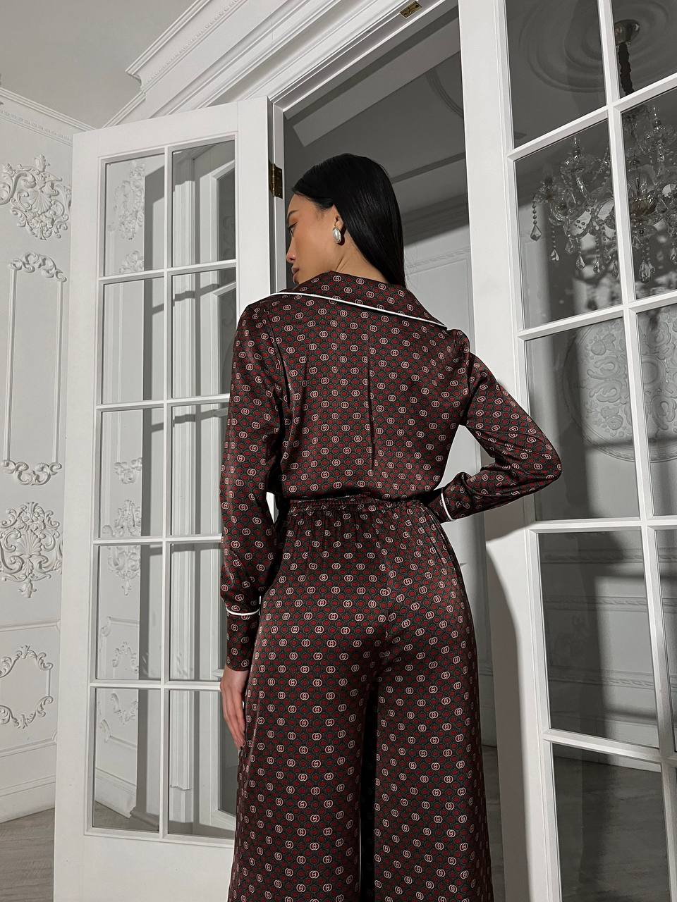 Woman in a patterned dress standing in a room with white walls and large windows.