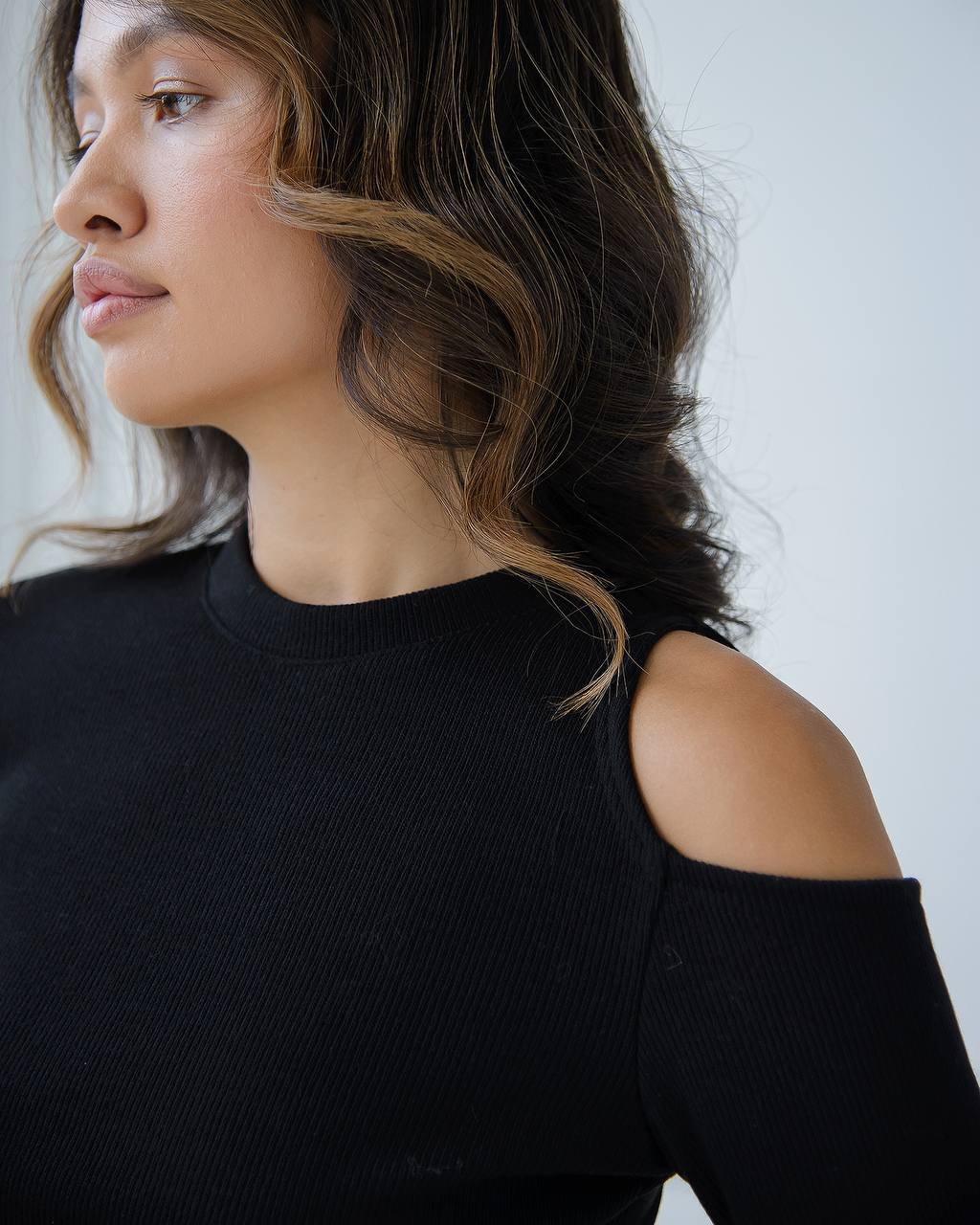 Woman wearing a black off-shoulder top against a plain background