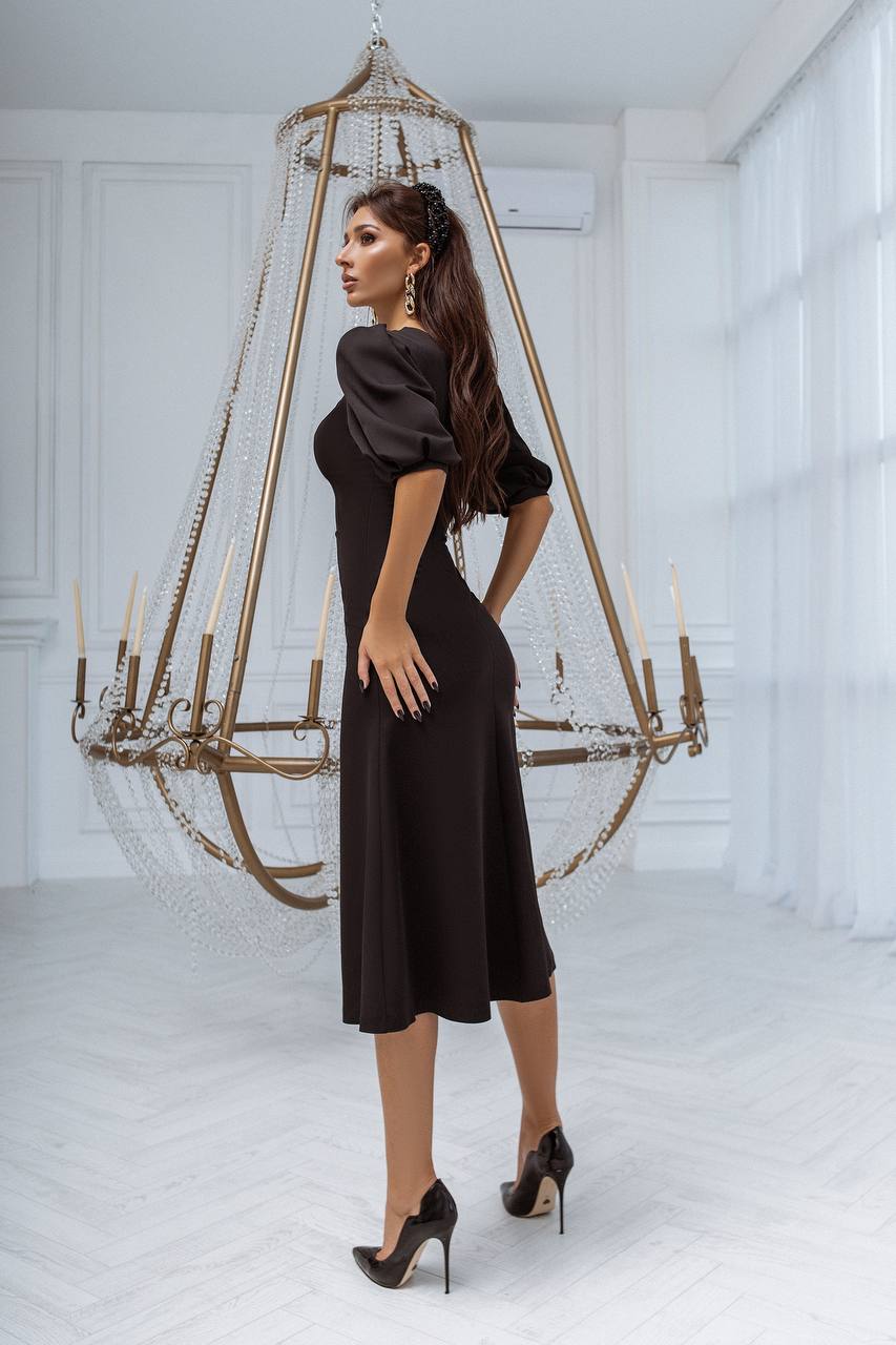 Woman in a black dress standing in a room with a large chandelier.