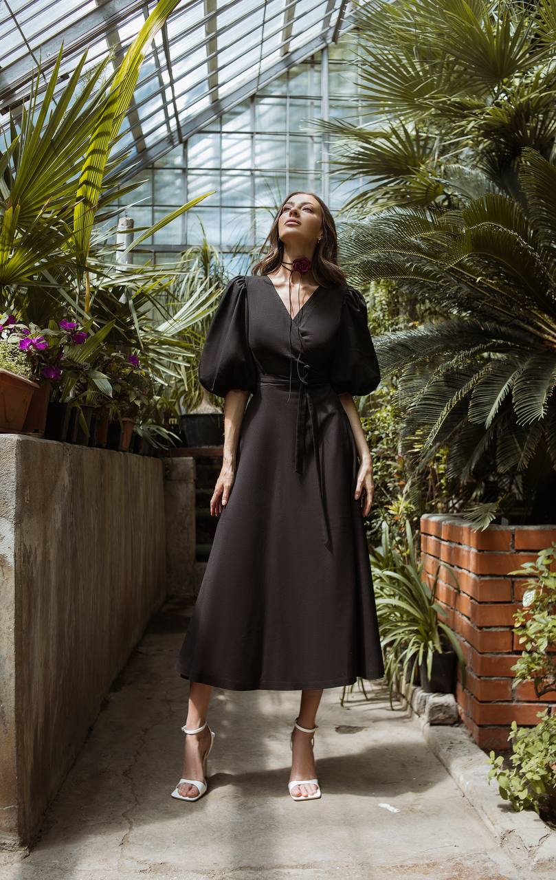 Woman in a black dress standing in a greenhouse filled with plants