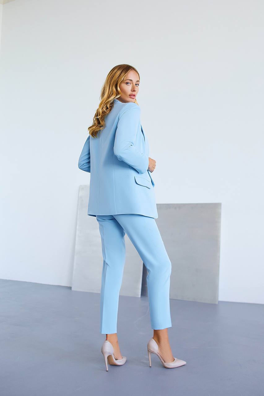 Woman wearing a light blue suit standing against a white background