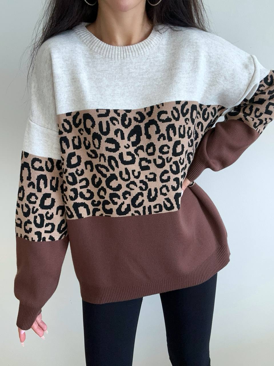 Sweater with color-block design featuring white, brown, and leopard print sleeves on a plain background.