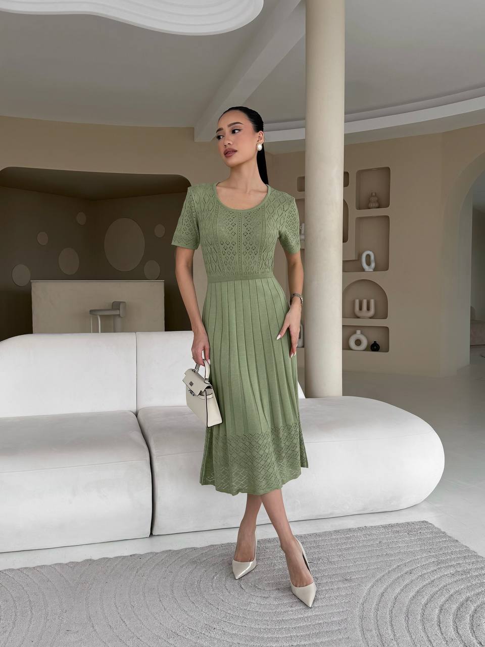 Woman in a green dress standing in a modern interior setting