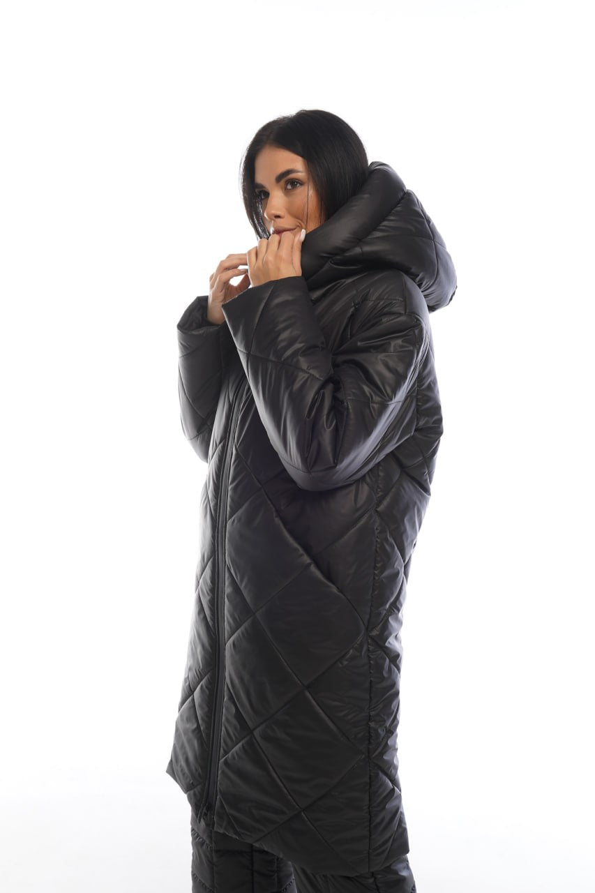 Person wearing a long black quilted jacket on a white background