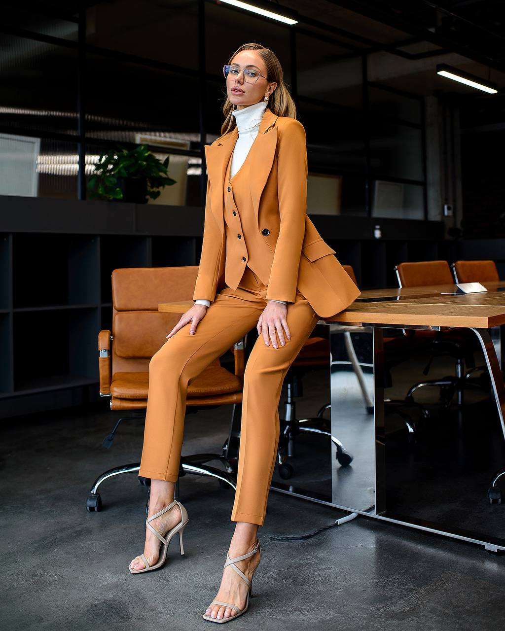 Woman in a mustard yellow suit sitting at a desk in an office setting