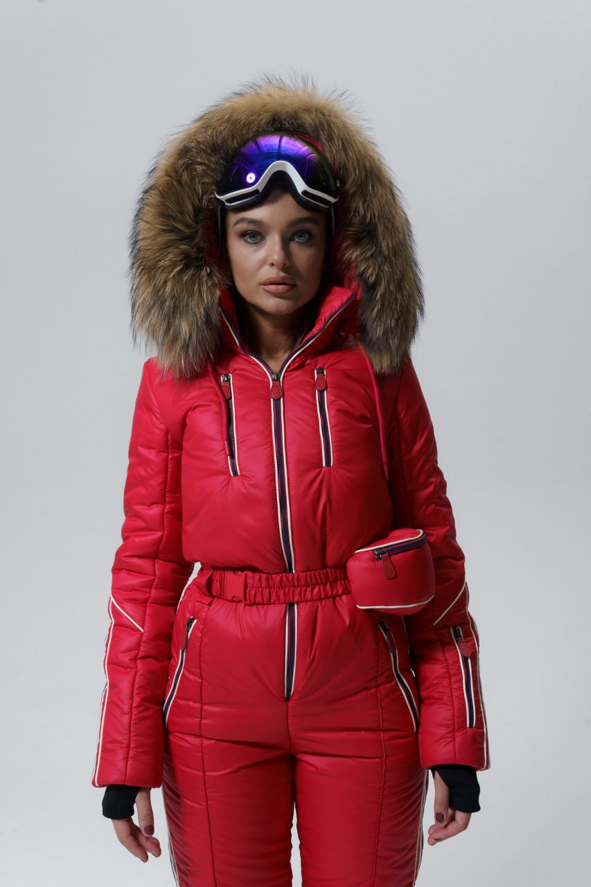 Person wearing a red ski suit with fur-lined hood on a gray background