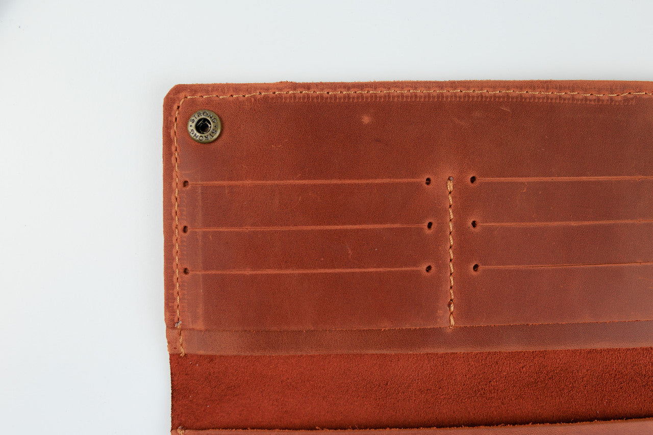 Close-up of the interior of a brown leather wallet or card holder, showing stitched card slots and a metal snap button on a white background.