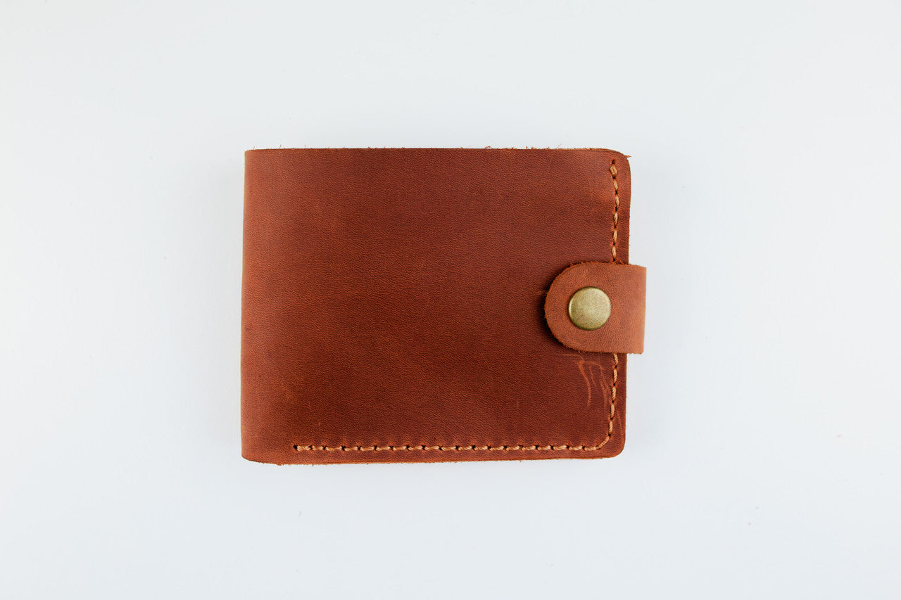 A brown leather bifold wallet with a snap-button closure, shown flat against a plain white background.