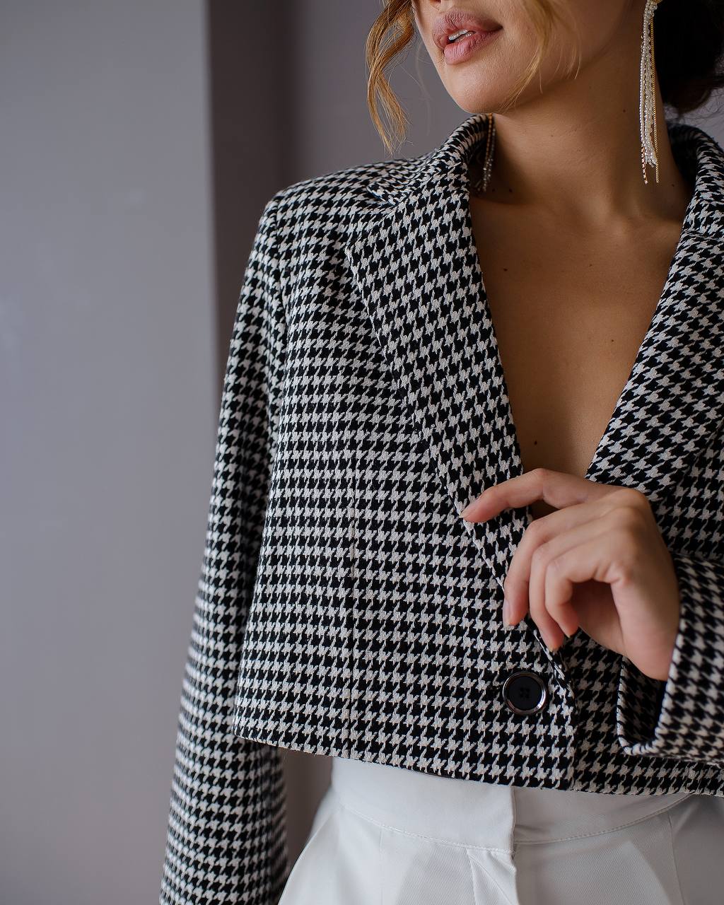Houndstooth patterned blazer worn by a person against a neutral background