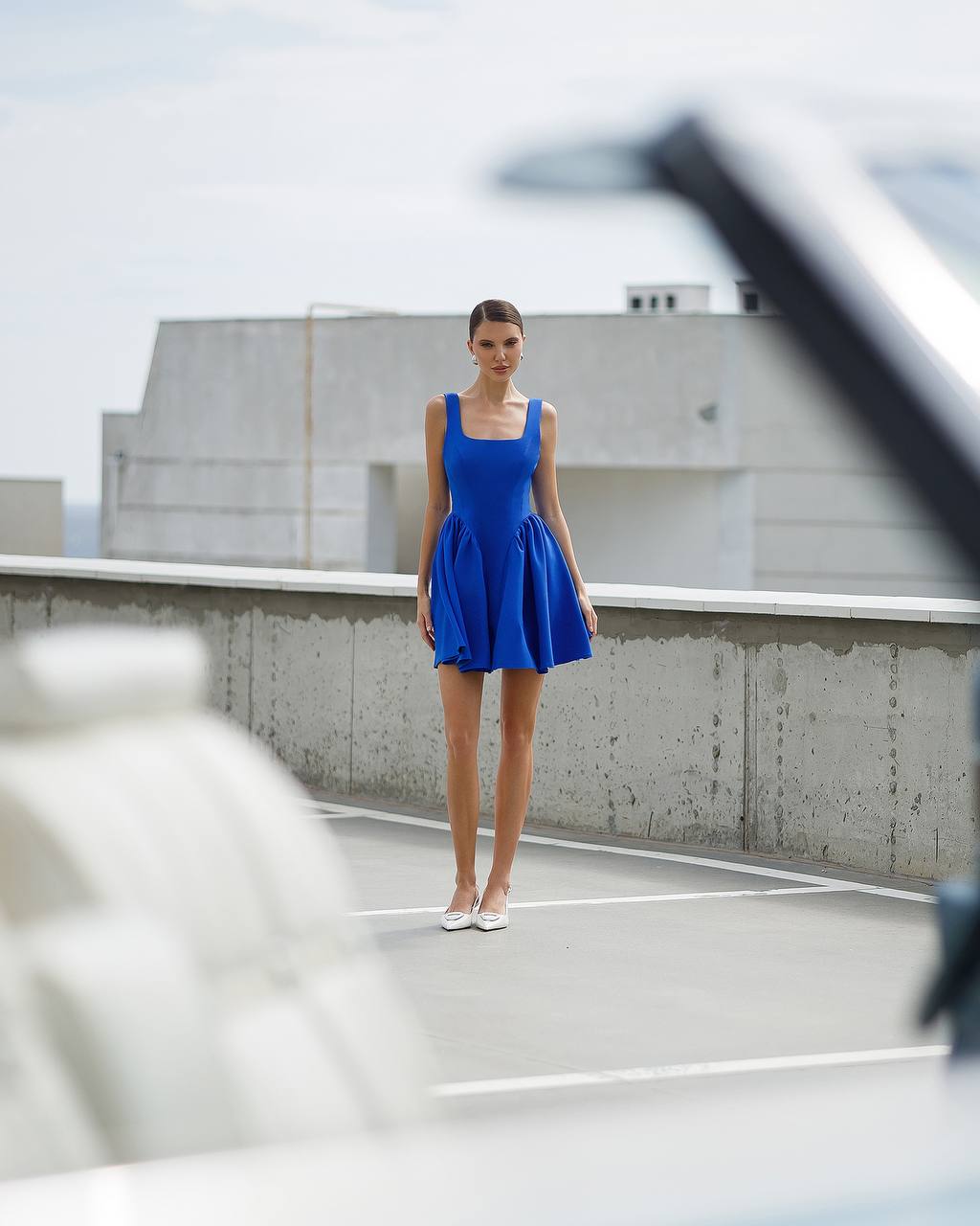 Woman in a blue dress standing on a rooftop with a building in the background