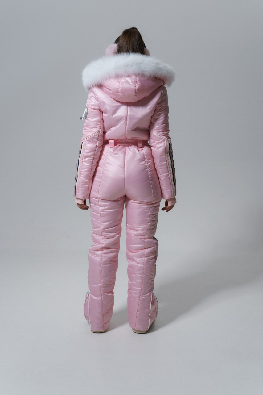 Person wearing a pink puffer suit with fur trim on a gray background