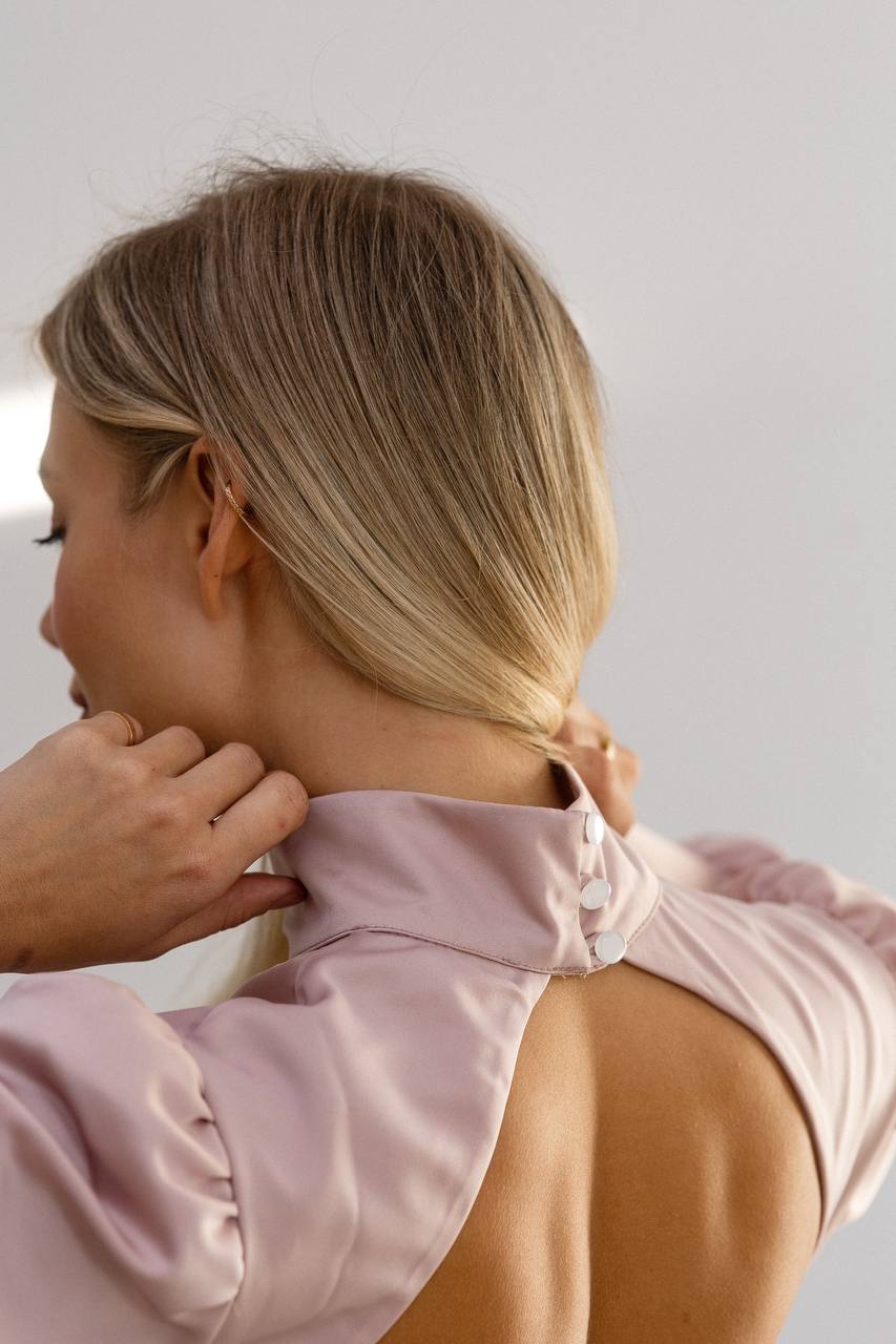 Person wearing a light pink jacket with a blurred background