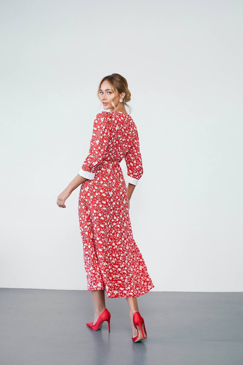 Woman wearing a red floral dress with white accents on a plain background
