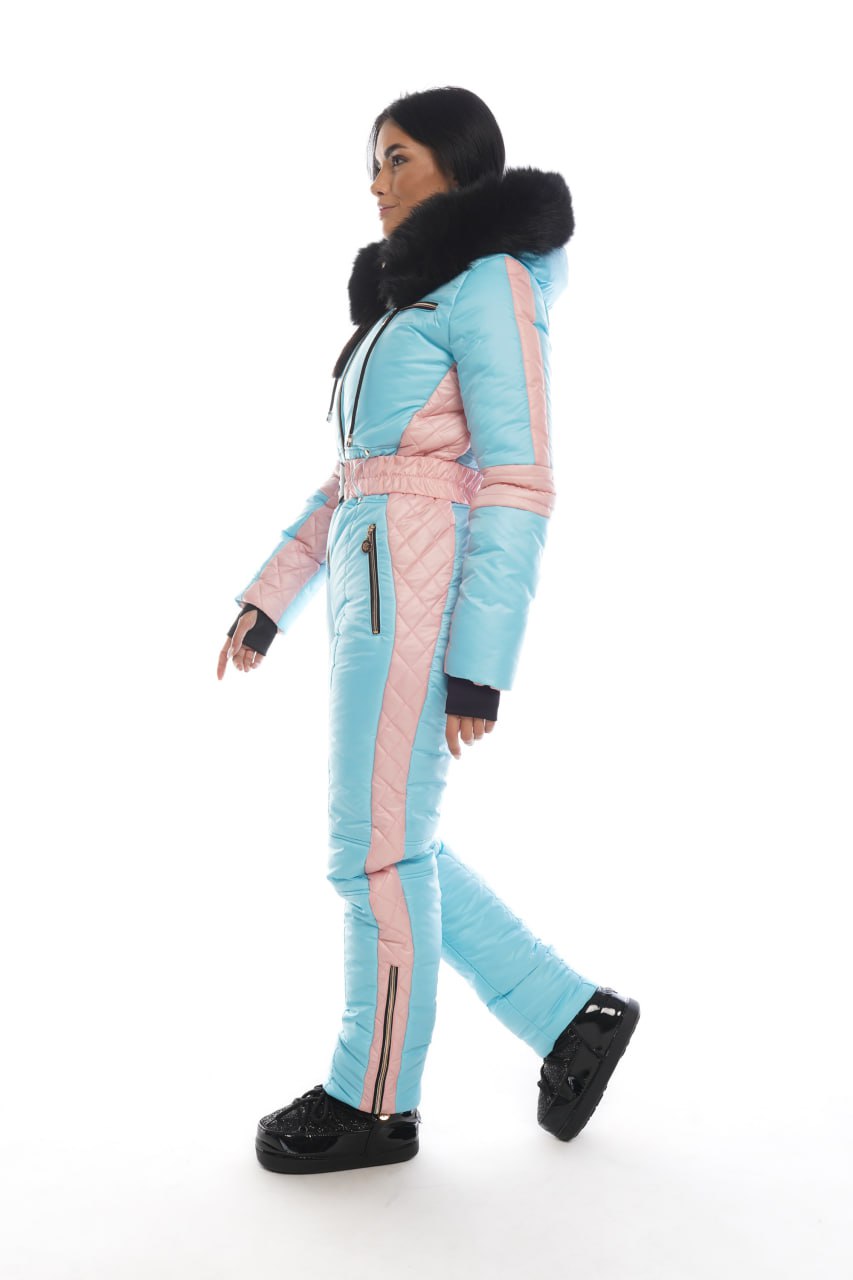Person wearing a light blue and pink snowsuit with black accents on a white background