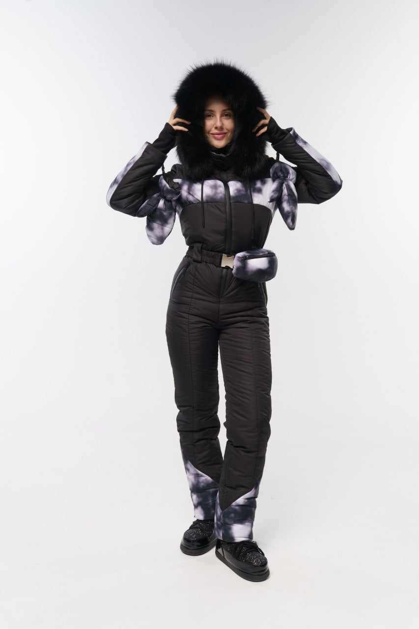Person wearing a black and gray patterned snowsuit with a fur-lined hood on a white background