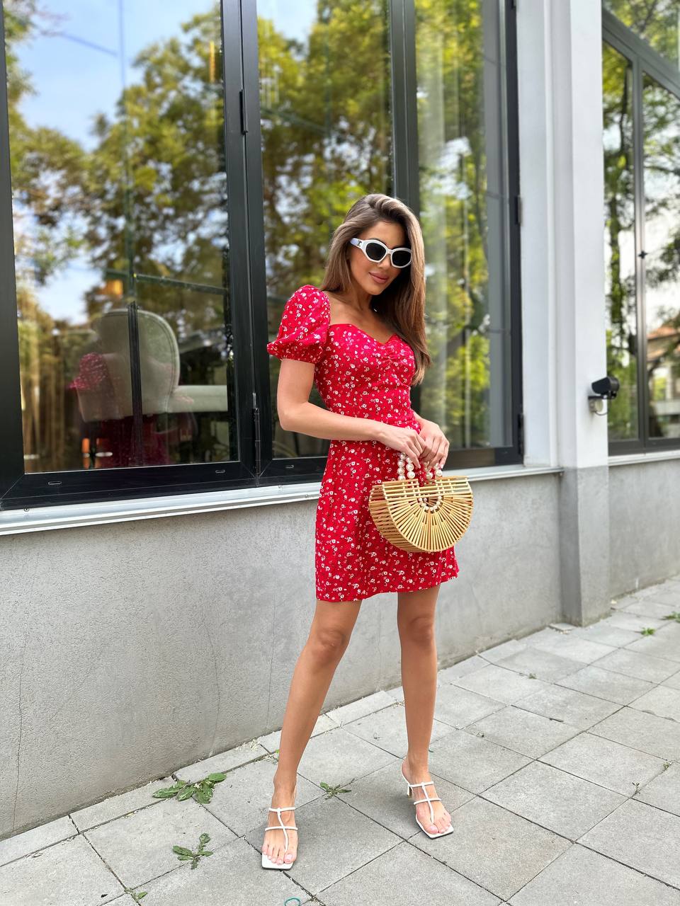 Woman in a red dress with white polka dots standing outside a building.