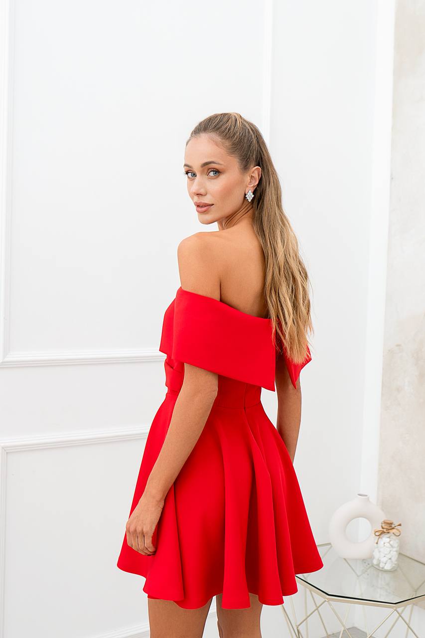 Woman wearing a red off-shoulder dress in a bright room.