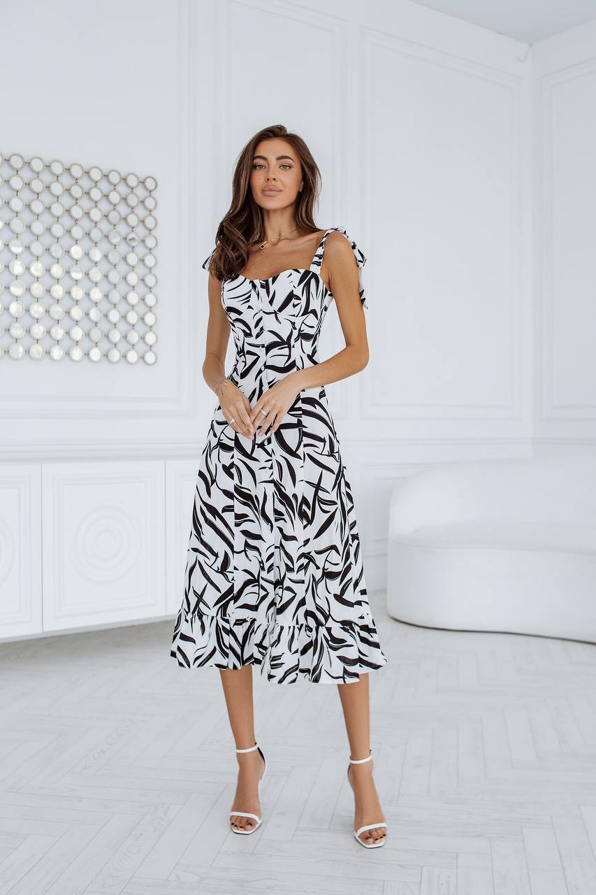 Woman wearing a black and white patterned dress in a minimalistic room.