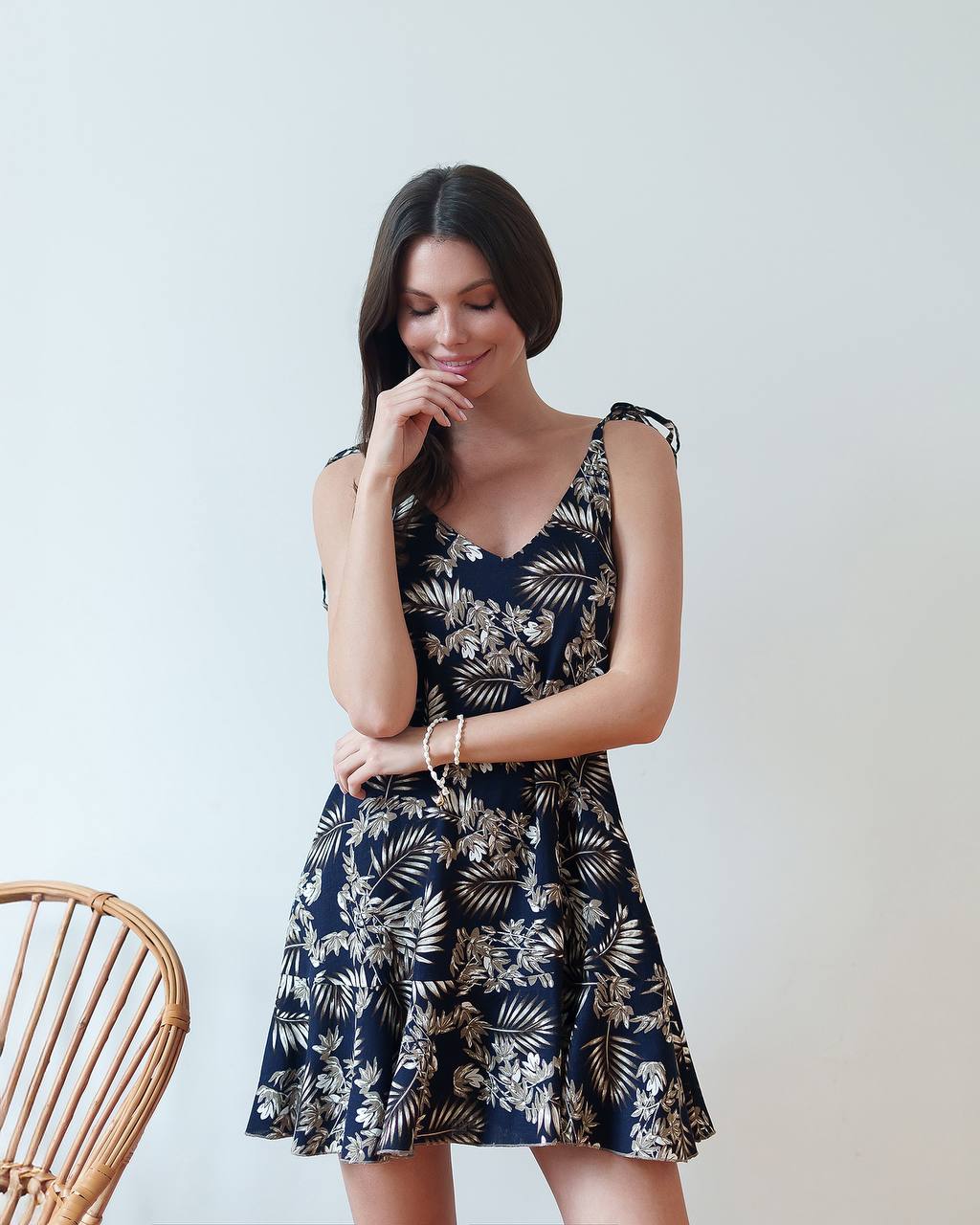 Woman wearing a navy blue dress with white floral pattern against a plain background