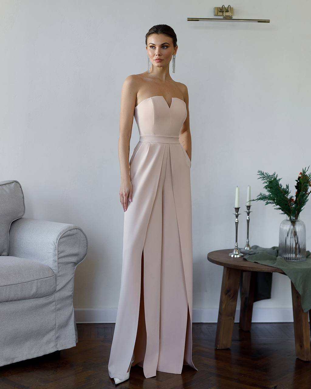 Woman in a strapless pink gown standing in a room with a couch and table.