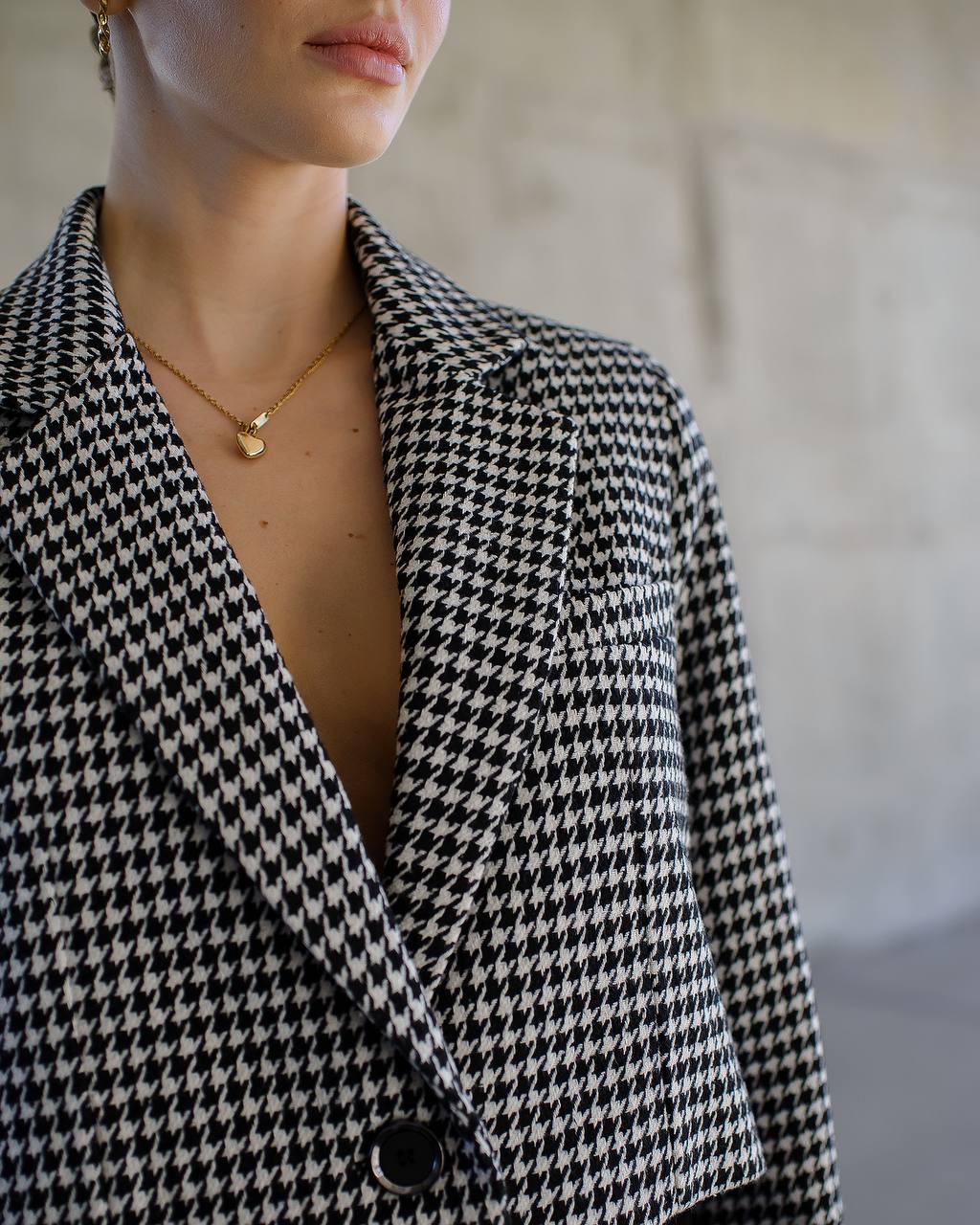 Person wearing a black and white houndstooth patterned blazer with a blurred background