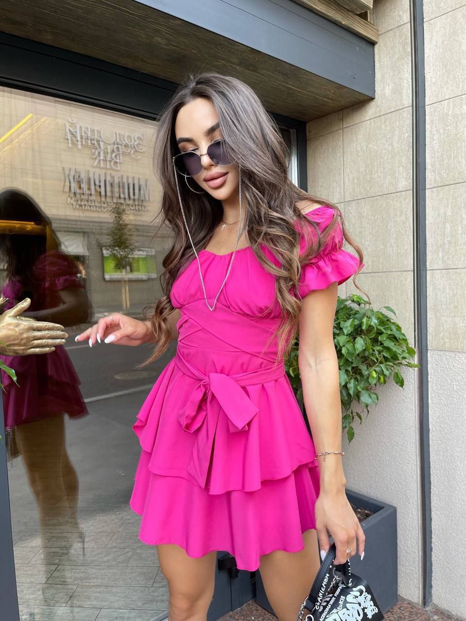 Woman in a bright pink dress standing outside a building