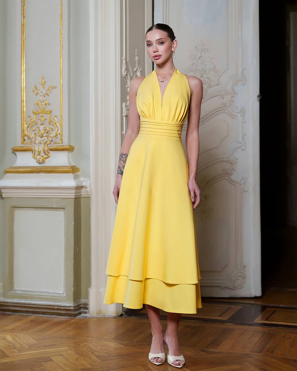 Woman in a yellow dress standing in an elegant interior setting