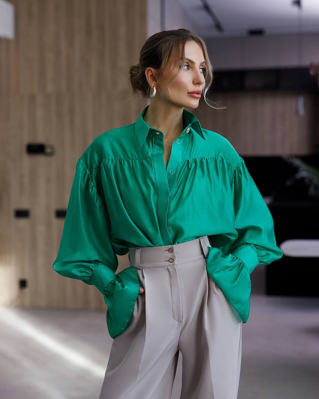 Woman wearing a green blouse and white pants in an indoor setting