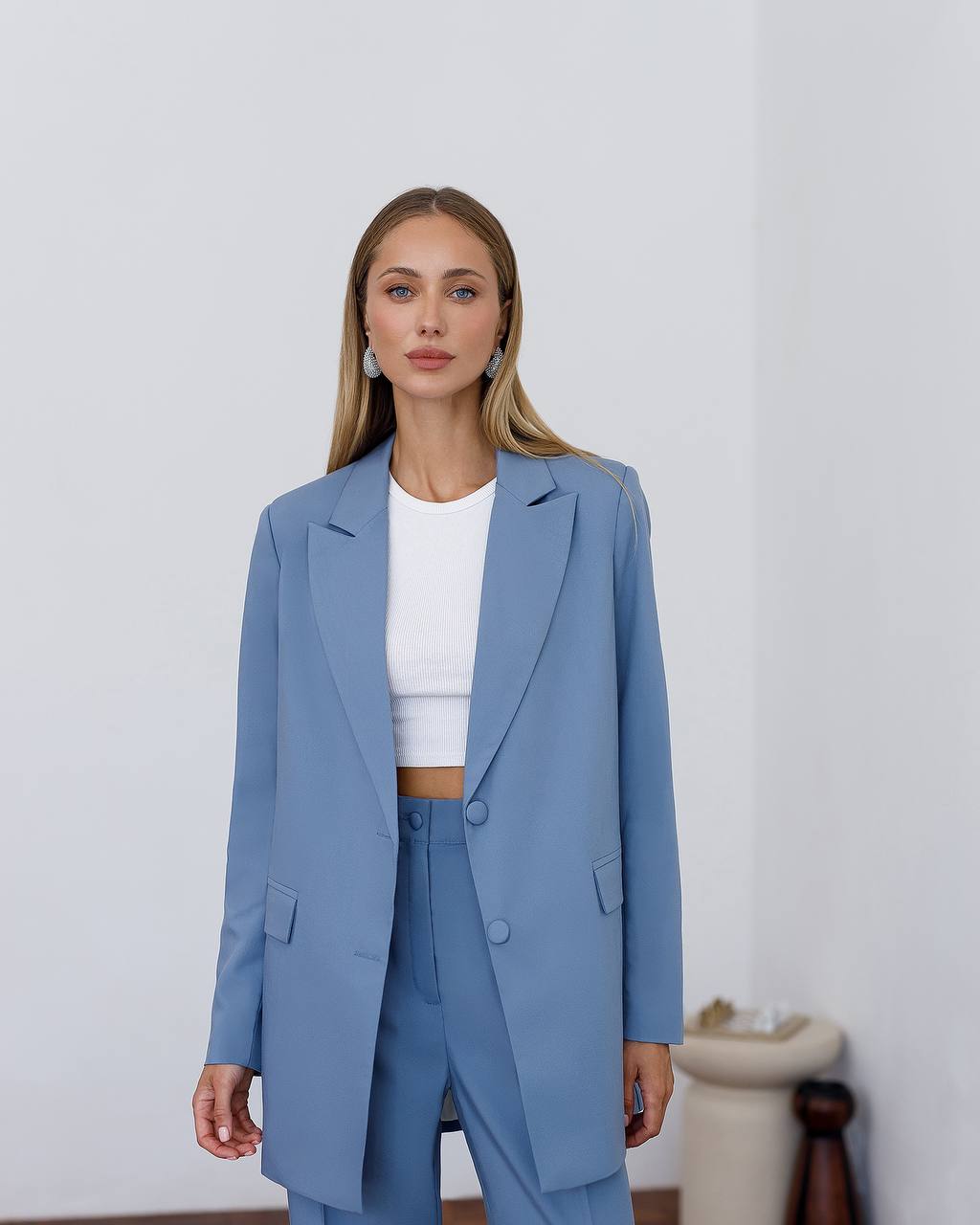 Woman wearing a blue suit with a white top against a plain background