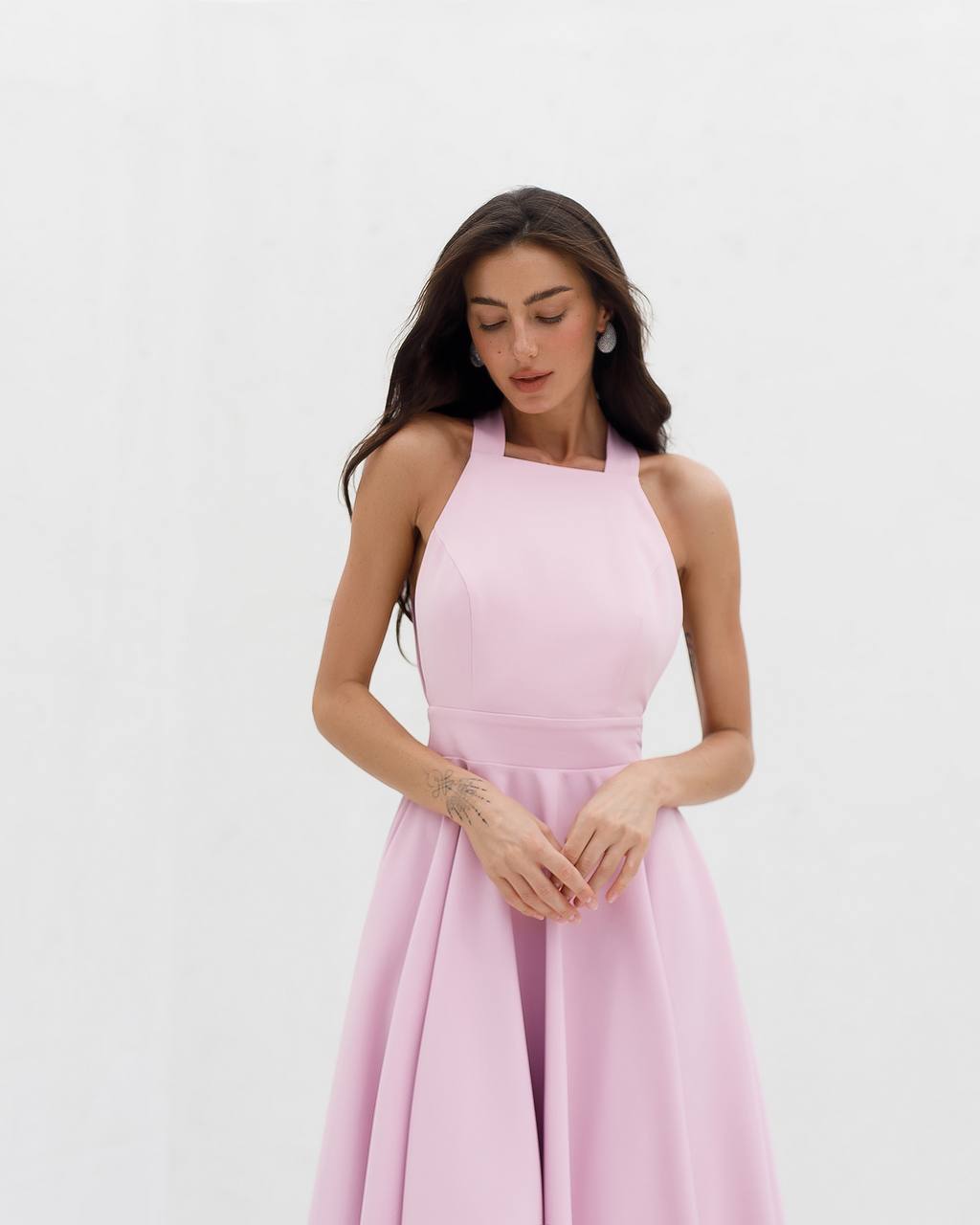 Woman wearing a pink halter neck dress on a white background