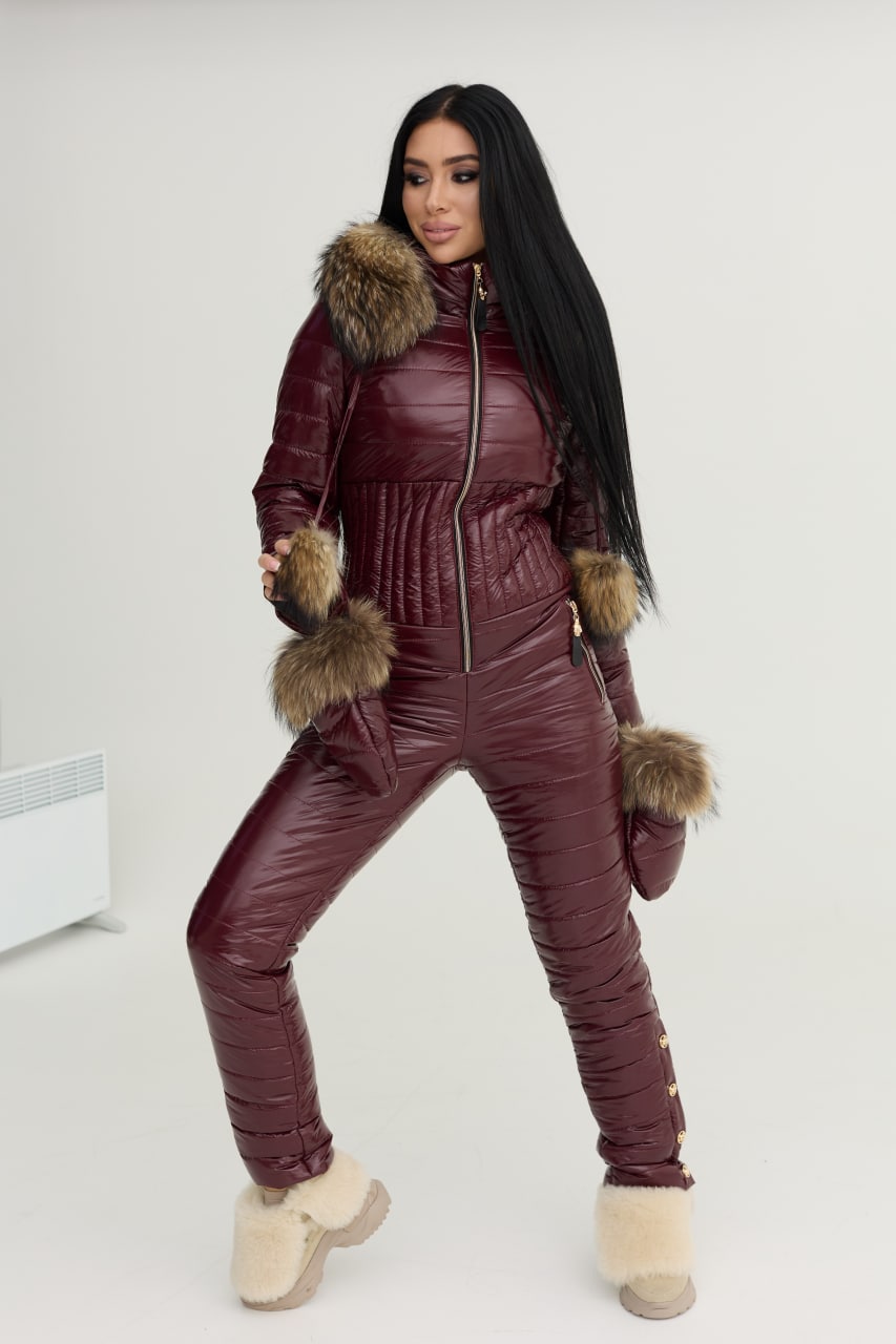 Woman wearing a maroon quilted jumpsuit with fur trim on a white background
