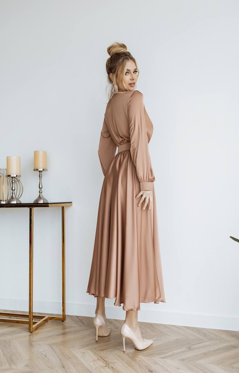 Woman in a beige dress standing in a room with a table and candles.