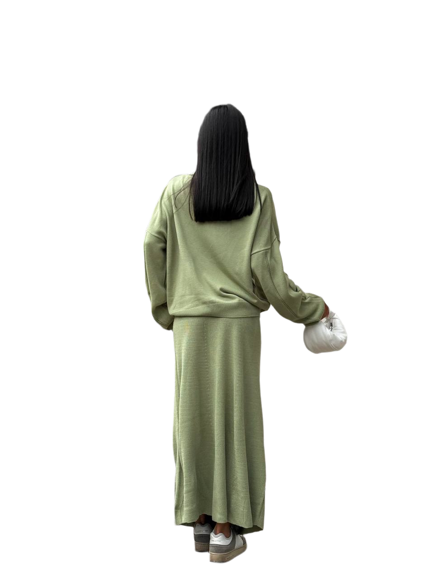 Person wearing a green outfit holding a white bag on a white background