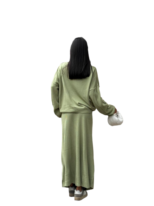 Person wearing a green outfit holding a white bag on a white background