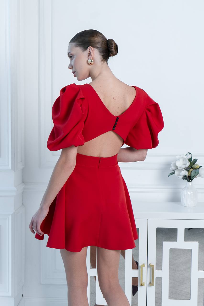 Woman wearing a red dress with puff sleeves in an elegant interior setting.