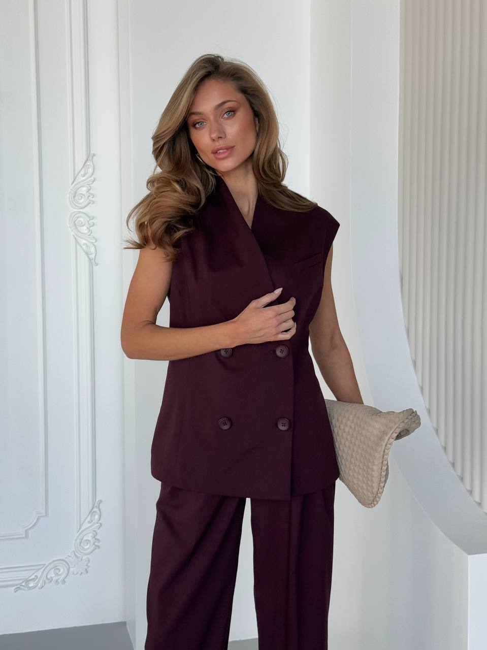 Woman wearing a burgundy suit with a white wall background