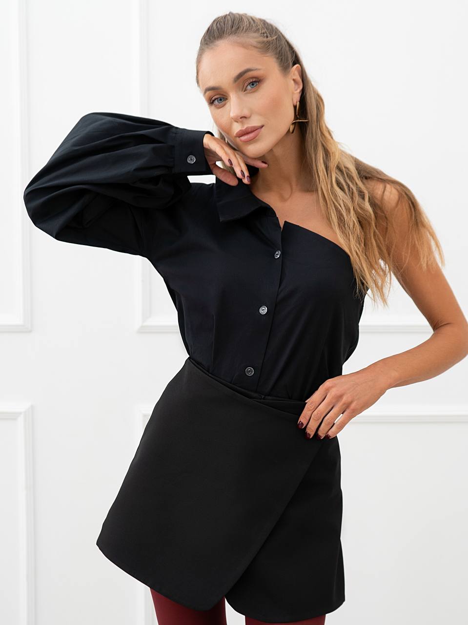Woman wearing a black one-shoulder dress against a white background