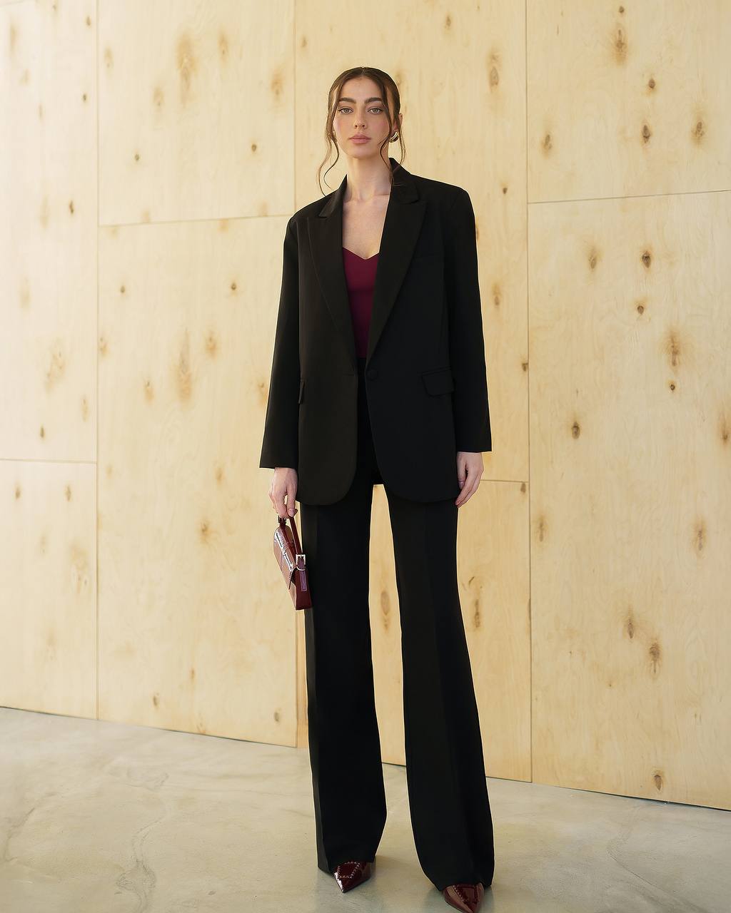 Woman wearing a black suit against a wooden paneled wall