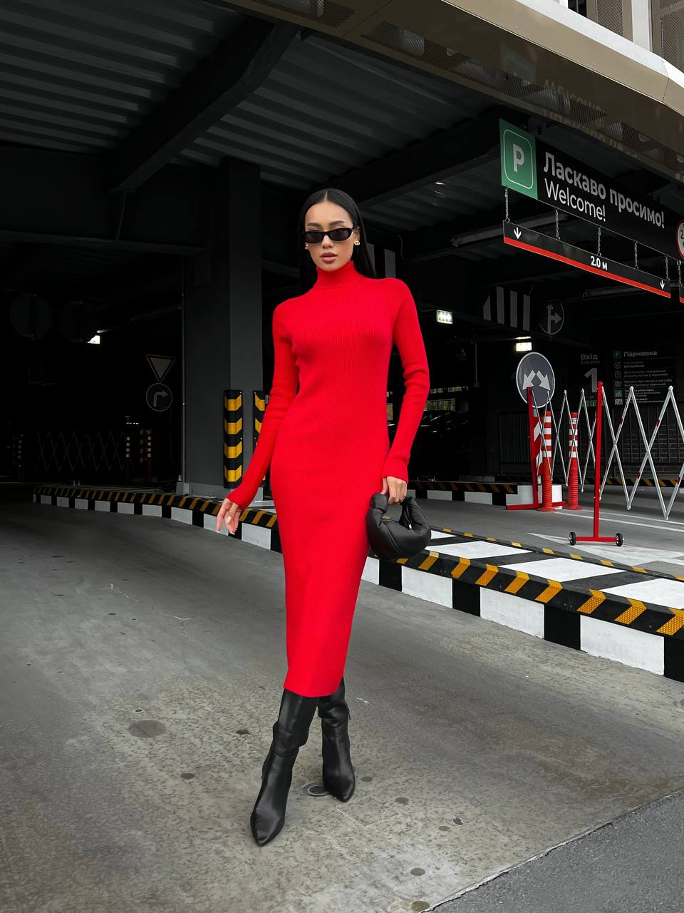 Person wearing a red dress and black boots in an urban setting