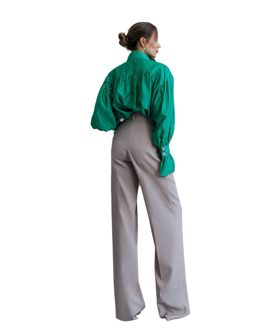 Person wearing a green blouse and gray pants on a white background