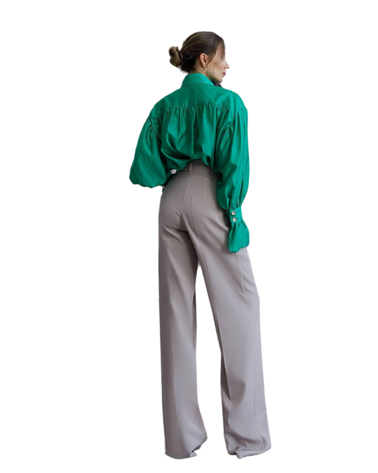 Person wearing a green blouse and gray pants on a white background