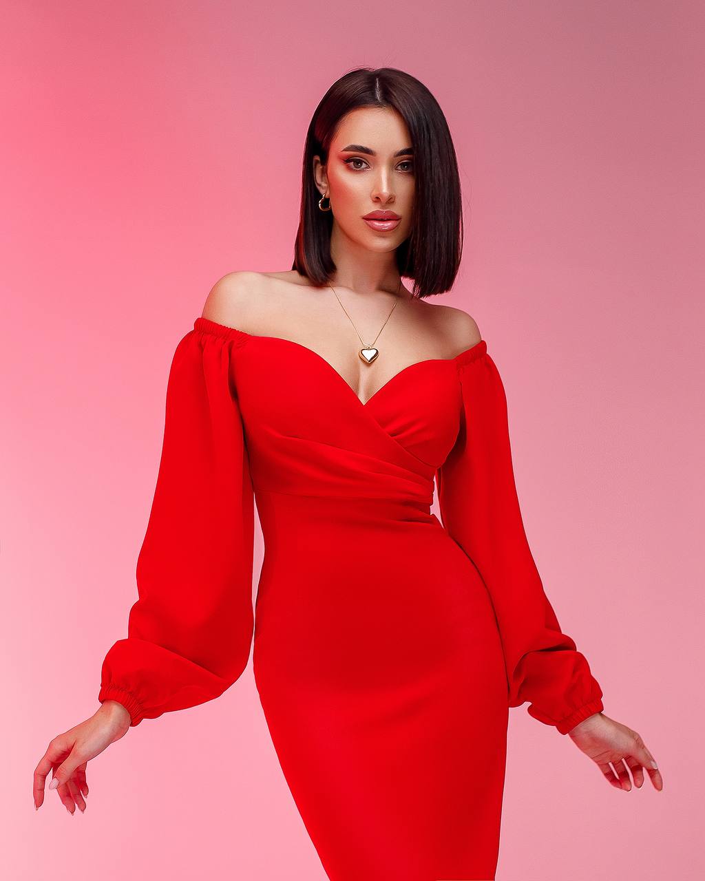 Woman wearing a red off-shoulder dress with long sleeves on a pink background