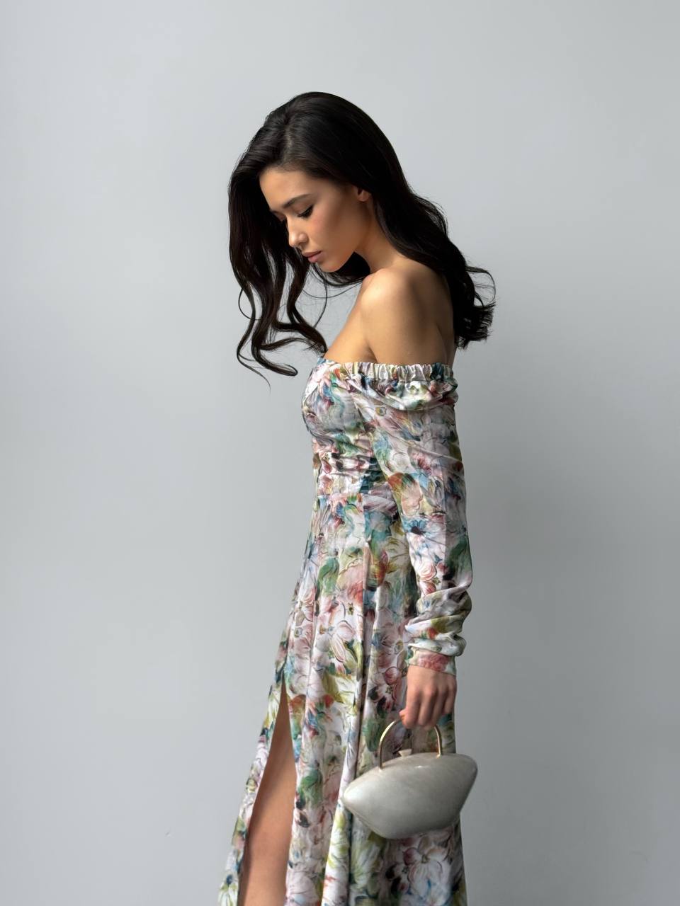 Woman wearing a floral off-shoulder dress against a plain background