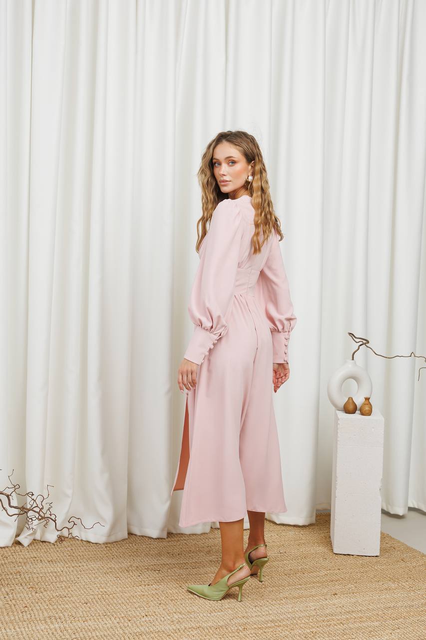 Woman in a pink dress standing in front of white curtains