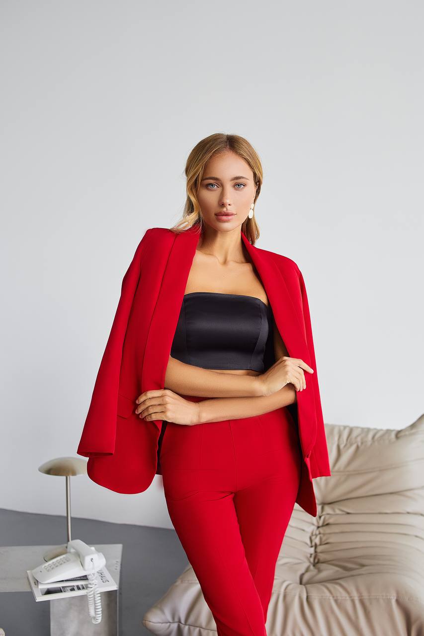 Woman wearing a red blazer and black top with a neutral background