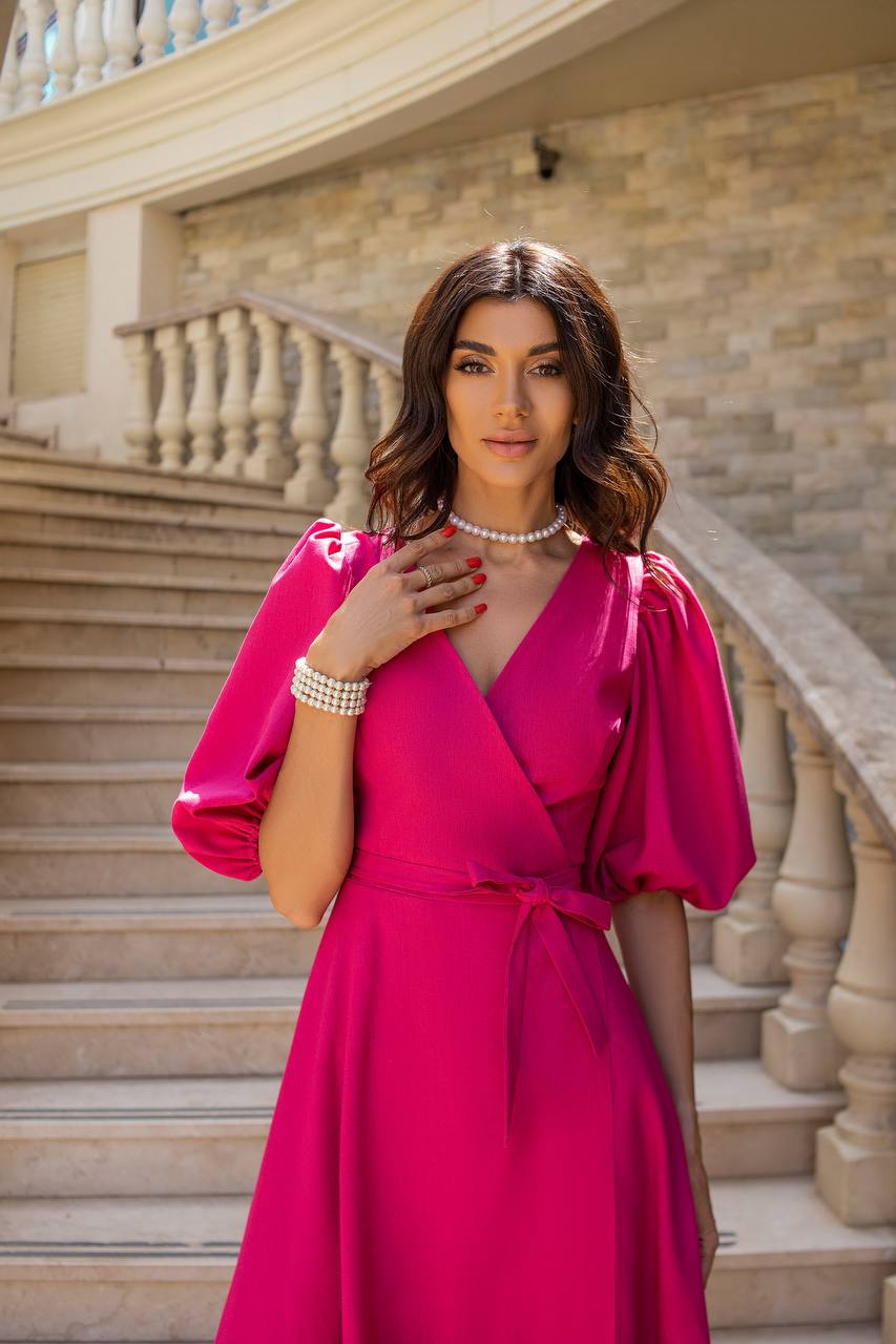 Woman in a pink dress standing on stone steps with a stone wall background