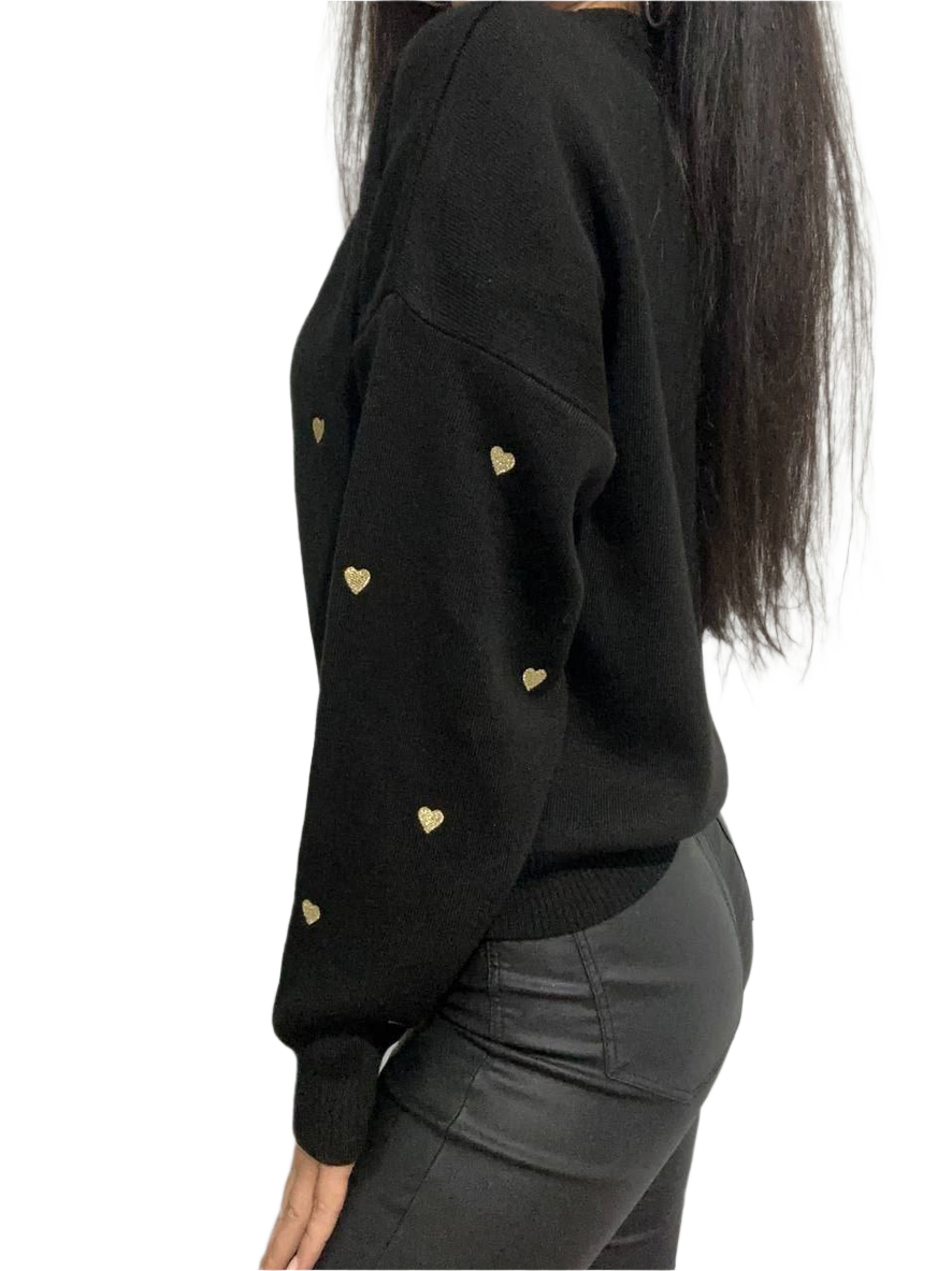 Black sweater with gold heart patterns worn by a person on a white background